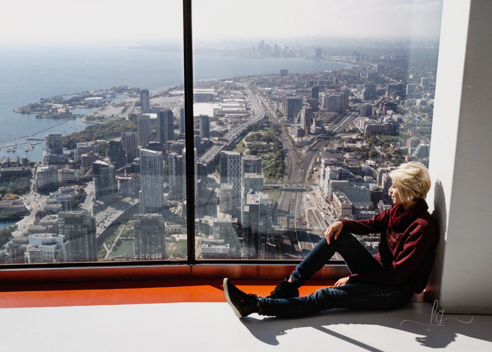 Lucy is looking out of the window of the CN Tower in Toronto.