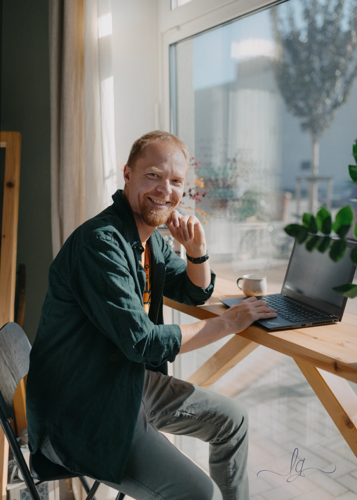 Smiling Lacko with a laptop by the window.